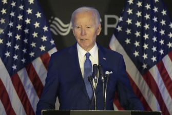 President Joe Biden speaking at a podium with American flags in the background