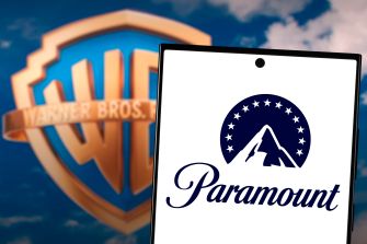 Warner Bros. logo in the background with a tablet screen displaying the Paramount logo in the foreground.