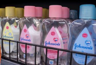 Johnson's plastic baby bottles with pink and yellow caps on a store shelf.