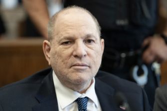 Close-up of a man in a dark suit and tie in a courtroom, with a serious expression.