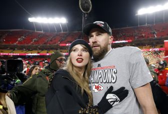 Taylor Swift and Travis Kelce pose together in a stadium after a Kansas City Chiefs game.