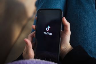Close-up of a hand holding a smartphone displaying the TikTok logo on the screen.
