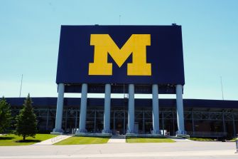 Front view of a University of Michigan building with a large yellow M logo on a blue sign.