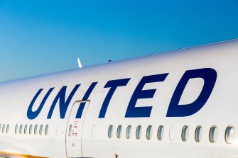Close-up of a United Airlines aircraft fuselage displaying the UNITED logo against a clear blue sky.