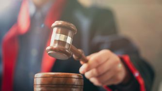 A wooden judge's gavel about to strike with a blurred courtroom background