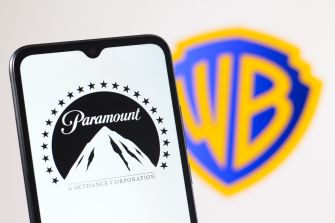 Smartphone screen showing Paramount logo with Warner Bros. logo blurred in the background.