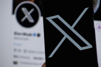 Close-up of the X logo displayed on a smartphone screen with a blurred app interface in the background.