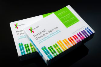 Two 23andMe Personal Genome Service boxes on a dark surface with rainbow-colored stripes.