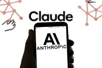 Close-up of a hand holding a smartphone displaying the AI Anthropic logo; the background shows the word Claude and orange network graphics.