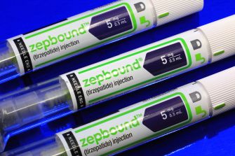 Close-up of three Zepbound tirzepatide injection syringes on a blue background