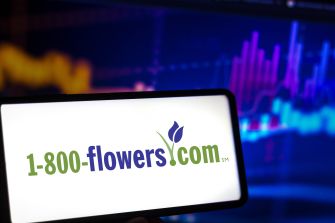 Close-up of a smartphone screen showing the 1-800-flowers.com logo with a colorful, blurred digital background.
