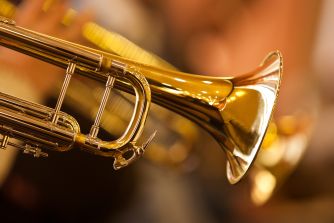 Close-up of shiny gold brass trumpets with their bells and valves visible.