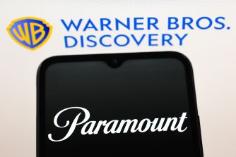 Warner Bros. Discovery logo in the background with a smartphone screen showing the Paramount logo.
