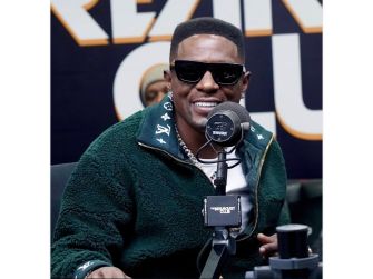 Torence Hatch, known as Boosie Badazz, wearing sunglasses and a green jacket, speaks into a microphone at a media appearance.