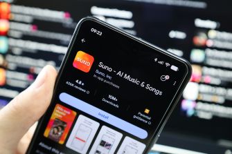 A hand holds a smartphone displaying the Suno AI Music & Songs app screen.