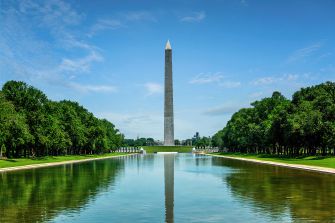 Lincoln Memorial Reflecting Pool in Washington, D.C., with the Washington Monument rising at the far end and trees lining both sides.
