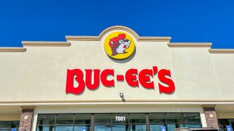 Exterior of a Buc-ee’s travel center with a large red Buc-ee’s sign and the beaver mascot on the storefront facade.