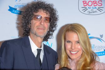 Howard Stern and his wife Beth Ostrosky Stern pose at a charity event, standing in front of a backdrop featuring animal-rescue logos.