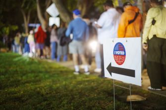 Missouri voters line up at a polling place, with an "I Voted" sign in the foreground.