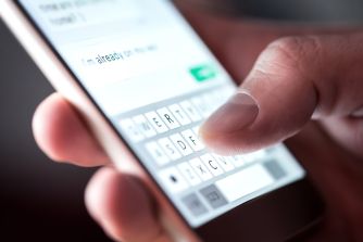 Close-up of a hand typing on a smartphone's on-screen keyboard.