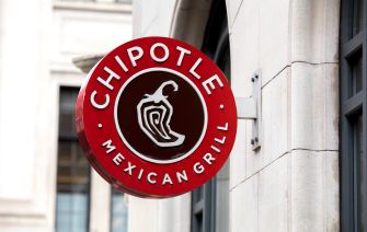 Round red Chipotle Mexican Grill sign with a white chili pepper logo mounted on the exterior of a building.
