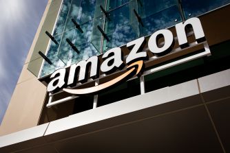 Exterior of an Amazon building with the Amazon logo prominently displayed on the facade.
