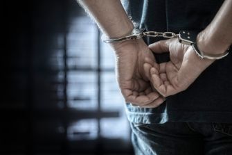 Jayson Reed in handcuffs, awaiting extradition to Maryland on four counts of second-degree assault and related charges related to the Morgan Wallen concert incident.
