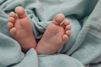Close-up of a newborn's feet with curled toes resting on a soft blue blanket.