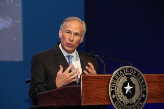 Greg Abbott, the governor of Texas, speaks at a podium with the Texas state seal.