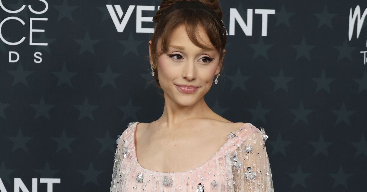 Photo: lawcommentary.com Ariana Grande stands on a red carpet in a pale pink, beaded gown with a sheer overlay