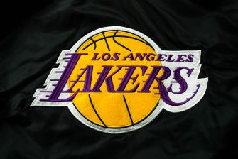Logo of the Los Angeles Lakers in purple and gold on a dark fabric background.
