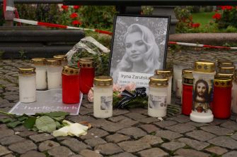 Memorial on a cobblestone surface for Iryna Zarutska, featuring a framed photo surrounded by lit candles and flowers.
