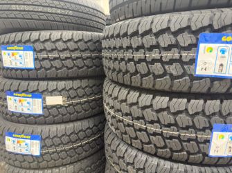 Stacks of tires with visible tread patterns and blue labels arranged in a storage area.