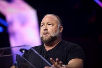 Alex Jones, founder of Infowars, speaks at a podium during a public appearance related to the Sandy Hook litigation.
