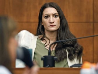Lindsay Clancy, the defendant in the Duxbury murder case, sits in a Plymouth Superior Court courtroom wearing a green top and beige cardigan with a serious expression.