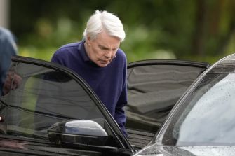 Michael Jeffries, former Abercrombie & Fitch CEO, with white hair wearing a blue sweater, stepping into a car.