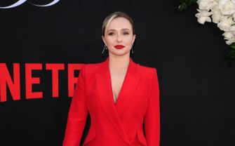 Hayden Panettiere posing on a red carpet in a bright red suit.