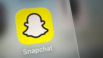 Close-up of the Snapchat app icon on a smartphone screen, featuring the white ghost logo on a yellow background.
