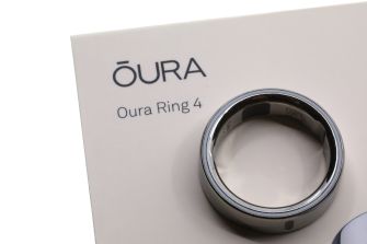 A silver Oura Ring 4 rests on a white display card printed with the ŌURA logo and the words “Oura Ring 4.”