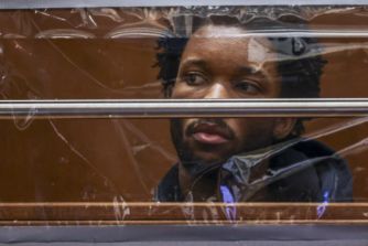 David Anthony Burke, also known as D4vd, sits in custody behind a glass barrier in a courtroom.