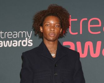 David Anthony Burke, also known as D4vd, stands on the Streamy Awards red carpet wearing a dark blazer.