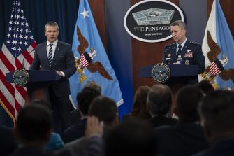 Two officials stand at separate podiums during a Pentagon briefing announcing mandatory testosterone testing for male service members aged 30 and older, with U.S. flags and the Pentagon seal in the background.
