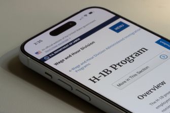 Close-up of a smartphone screen displaying a government web page titled H-1B Program.