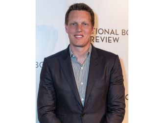 David Ellison poses in a suit and striped shirt at an event.