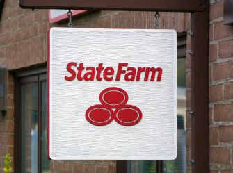 State Farm sign hanging outside a brick building.