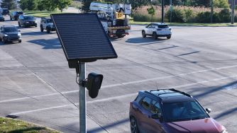 A solar-powered automated license plate reader monitors vehicles at an intersection.