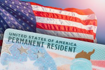 U.S. Permanent Resident Card displayed in front of a waving American flag.