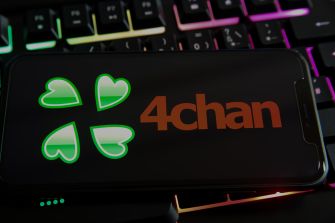 4chan logo displayed on a black device resting over a colorful backlit computer keyboard.