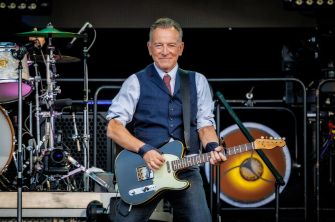 Bruce Springsteen performs onstage with an electric guitar.