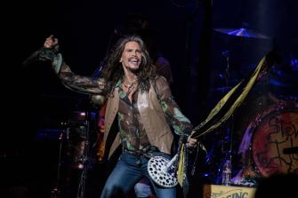 Steven Tyler performs onstage with a patterned guitar during an Aerosmith concert.